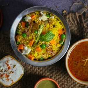 Top view of vibrant Indian biryani with curry and raita on a rustic setting. Perfect for food lovers.